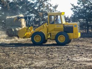 Our John Deere payloader hauls a bale to the cows.