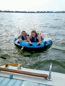 Phil's oldest two daughters - Trish and Sarah - smile on the tube behind the boat before Phil tries to throw them off.
