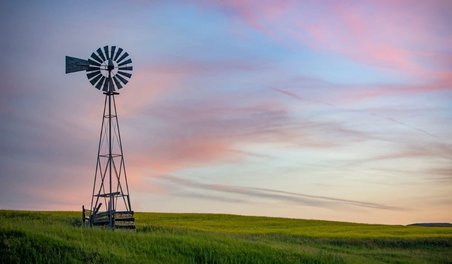A windmill for livestock in a green pasture. Windmills can be a great metaphor for the winds of the spirit and the living water only God provides for our souls.