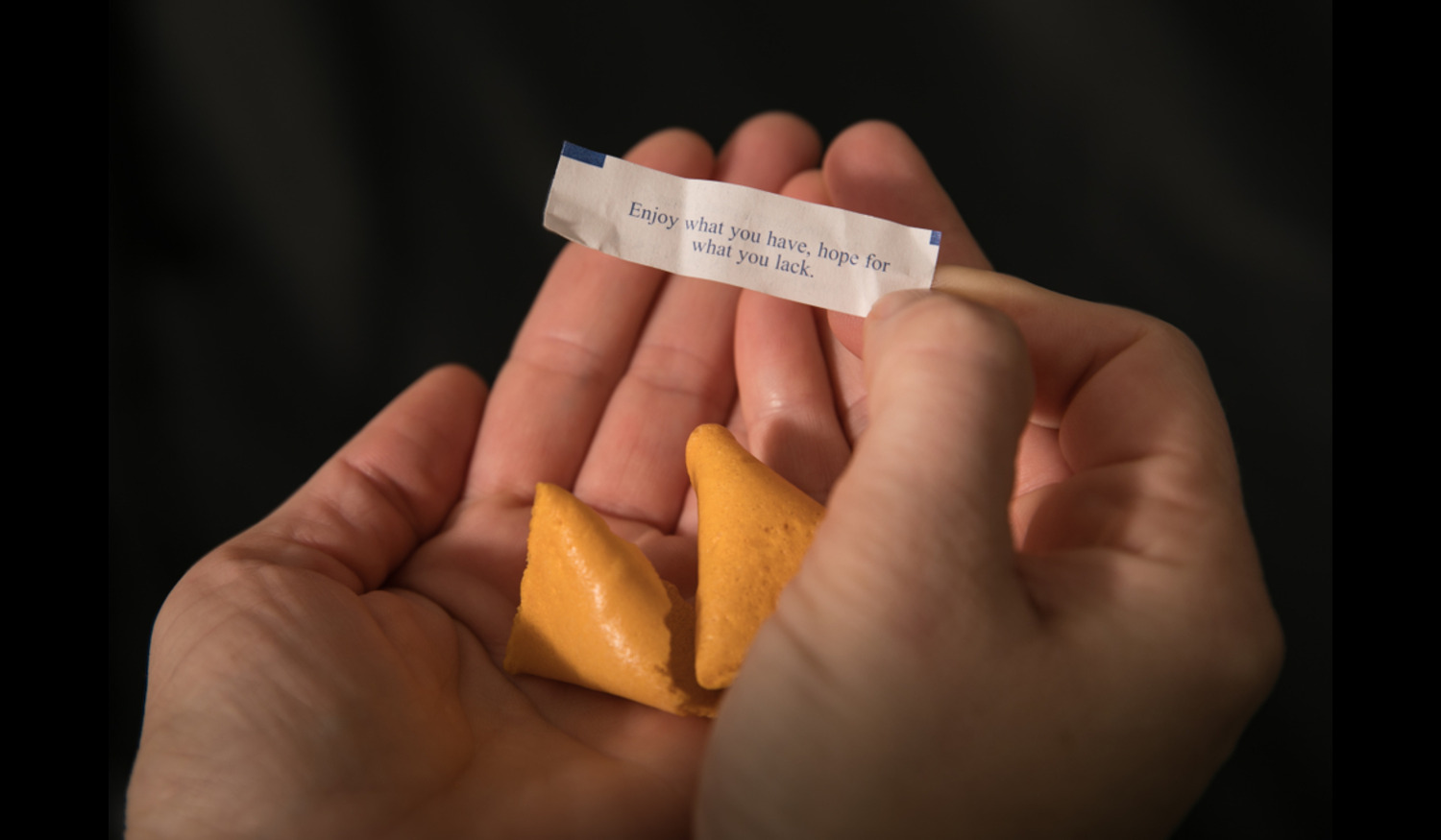 hands holding an opened fortune cookie