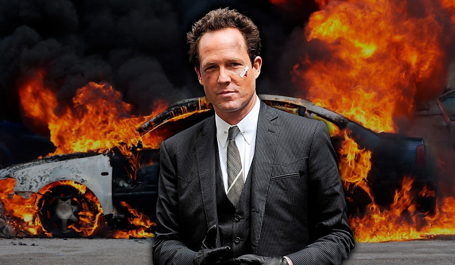 The "mayhem guy" stands in front of a burning car